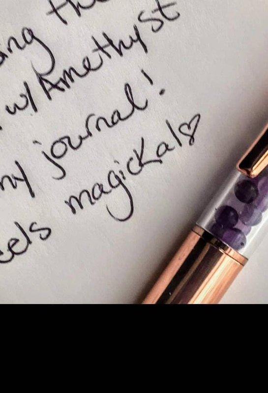 Amethyst crystal pen resting on a handwritten journal page with rose gold details.