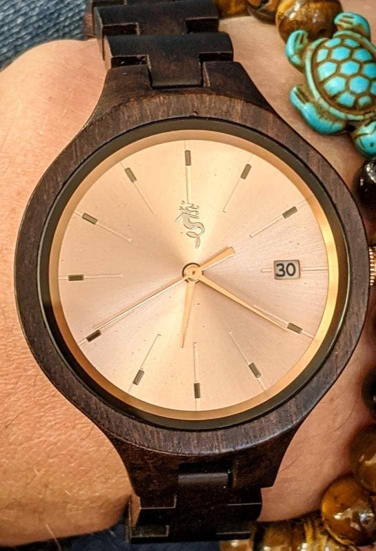 Close-up of Nymph Ki wooden watch with tigerβs eye bracelet and turquoise turtle charm.
