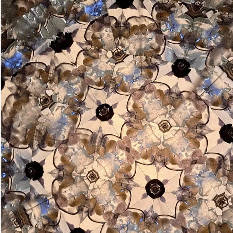Intricate kaleidoscope pattern made from crystals and minerals, forming a floral mandala design with blues and creams.