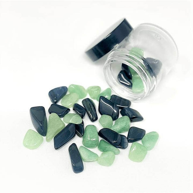 Blue Tiger’s Eye and Green Aventurine stones spilling from a glass jar on a white background for water infusion.

