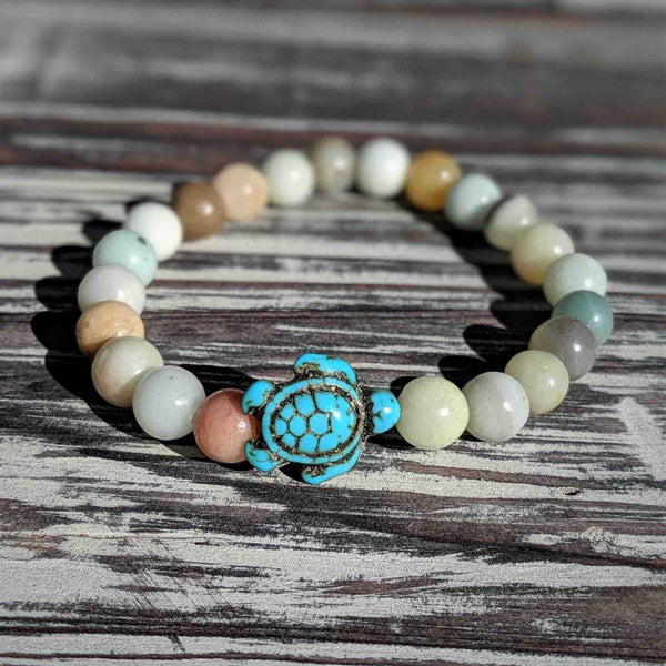 Beaded bracelet with druzy agate beads and a turquoise center piece on a wooden surface