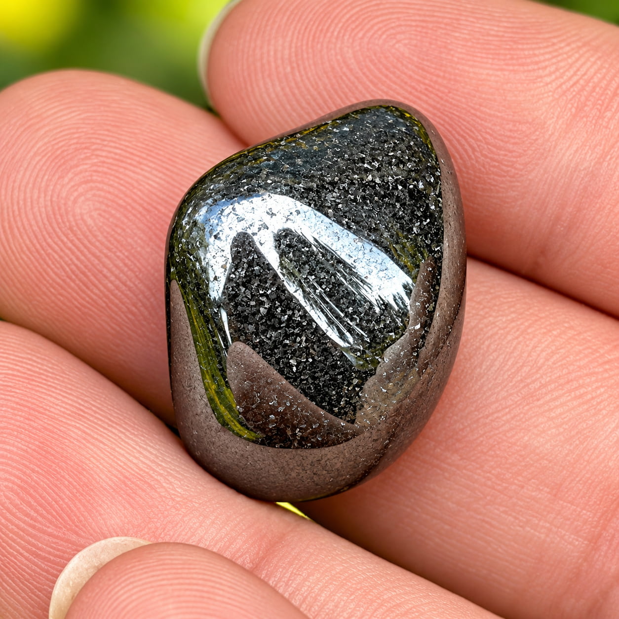 A single polished hematite stone in an open hand.