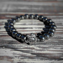 Hematite beaded bracelet with a  turtle charm on a wooden surface