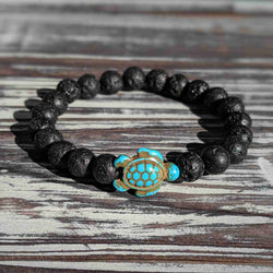 Black lava rock beaded bracelet with a turtle charm on a wooden surface
