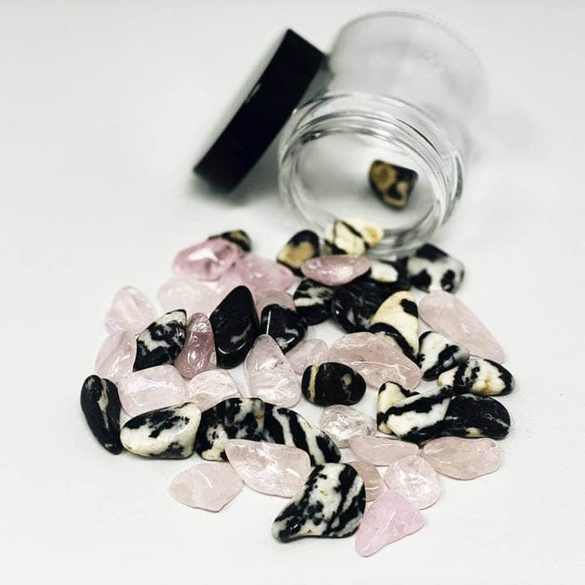 Rose Quartz and Zebra Marble stones spilling from a glass jar on a white background for emotional healing and heart-centered energy.
