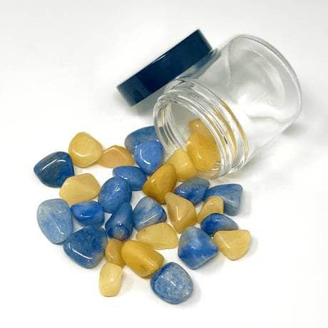 Blue Quartzite and Yellow Quartz stones spilling from a glass jar on a white background for personal growth and hydration.

