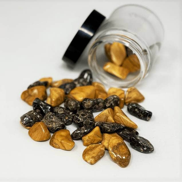 Yellow Jasper and Turritella Agate stones poured from a glass jar for grounding and spiritual hydration rituals.
