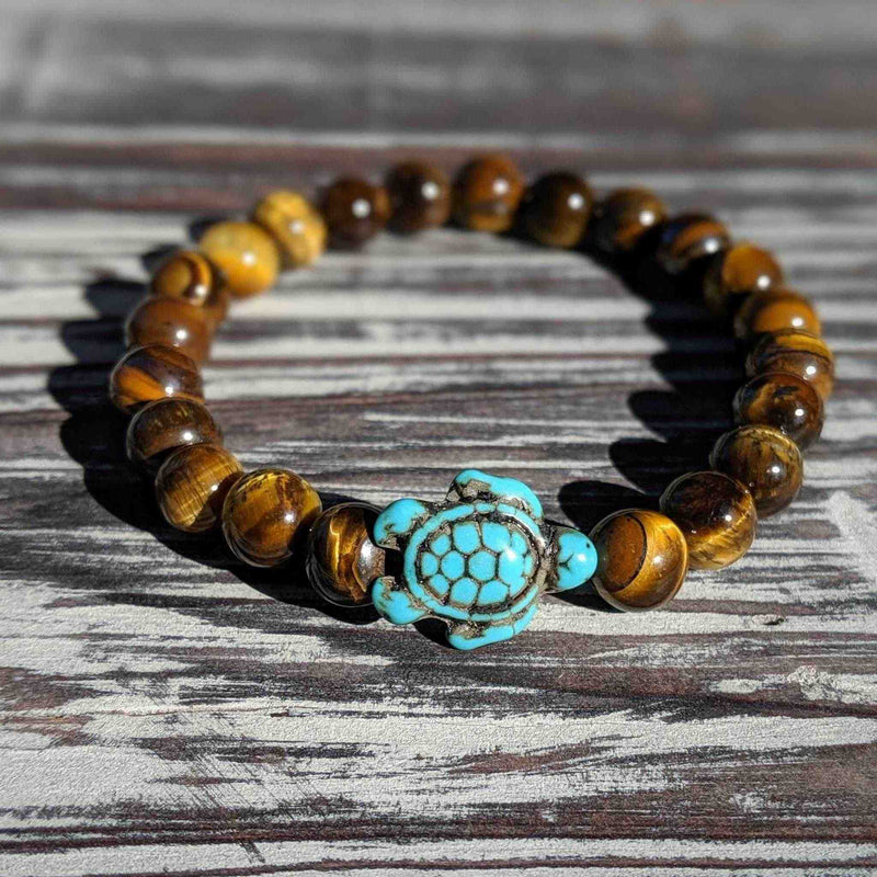 Bracelet with tiger eye beads and turquoise turtle charm on a wooden surface