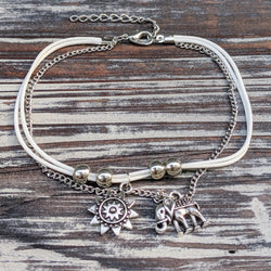 Silver tone elephant anklet with sun charm and adjustable clasp on wood background.