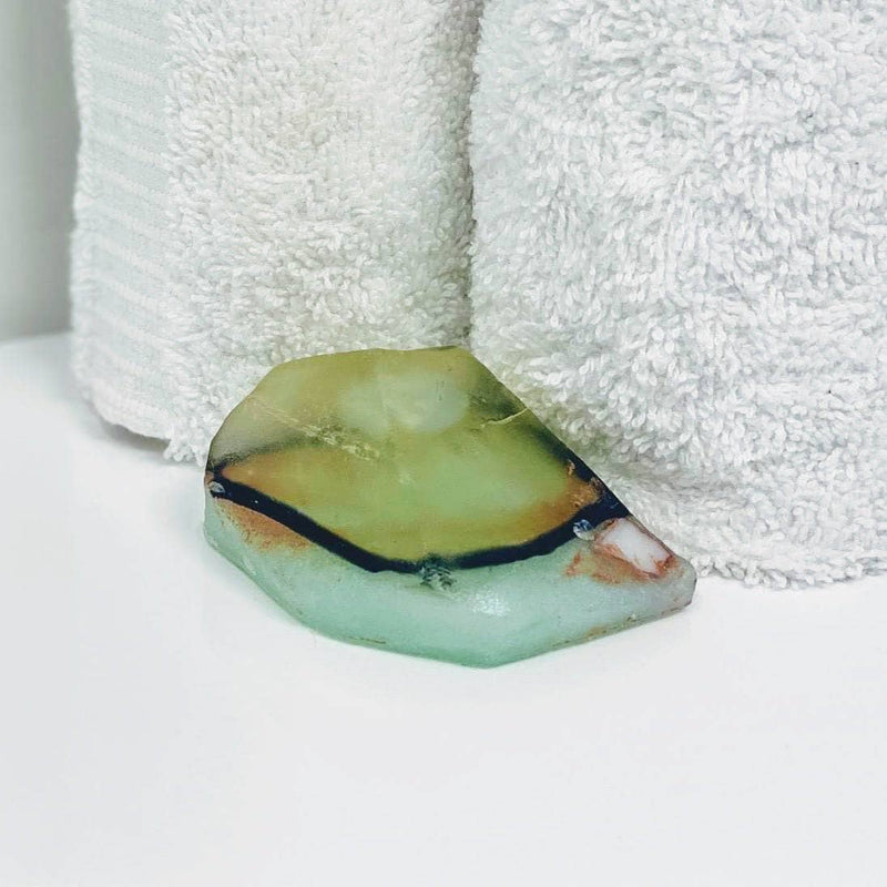 Lemongrass and aquamarine crystal soap displayed with a hand towel in the background.