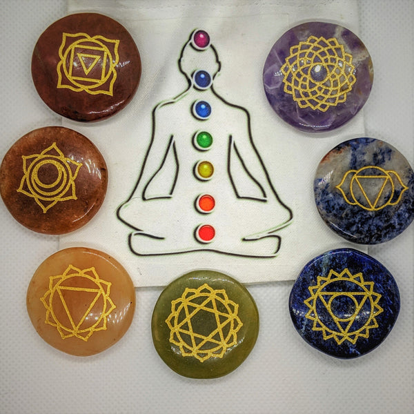 Seven engraved agate chakra stones arranged around a meditating figure illustration.