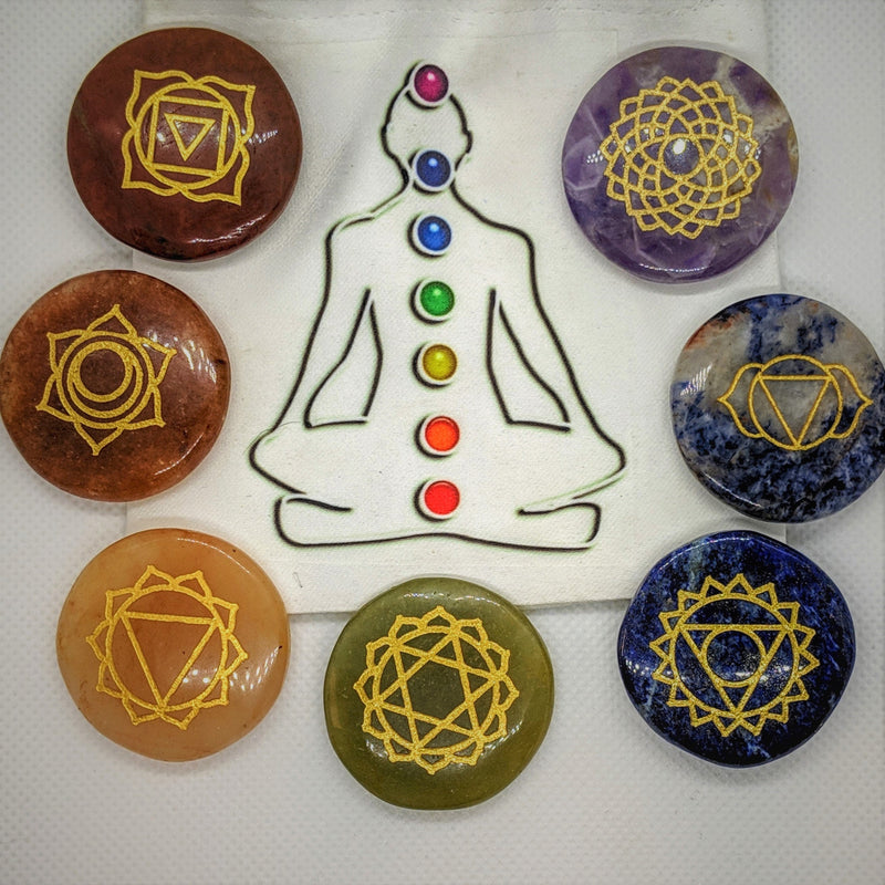Seven engraved agate chakra stones arranged around a meditating figure illustration.