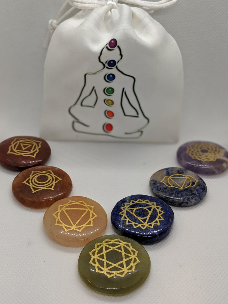 Handmade agate chakra stones in front of white Buddha pouch used for spiritual storage.