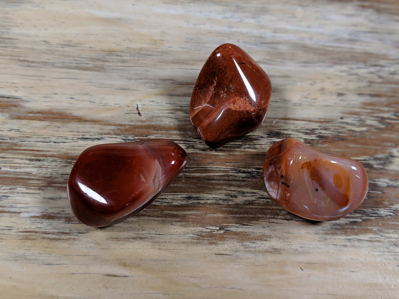 Polished red jasper and carnelian stones aligned with the root chakra, offering grounding and stability.
