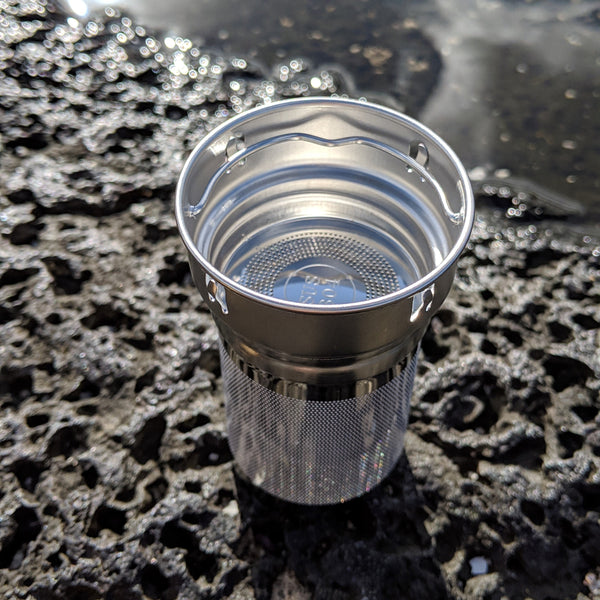 Crystal Ki stainless steel tea strainer shown near water, designed to fit Nymph Ki water bottles.