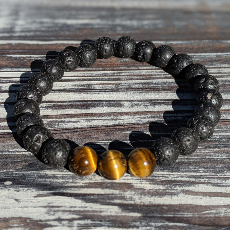 Lava Rock and Tiger’s Eye stretch bracelets shown side by side on wood, highlighting natural textures.