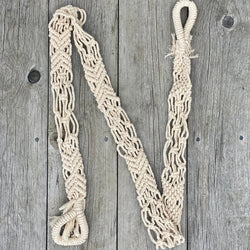 Handwoven macrame yoga strap laid out flat on a wooden surface with looped ends.