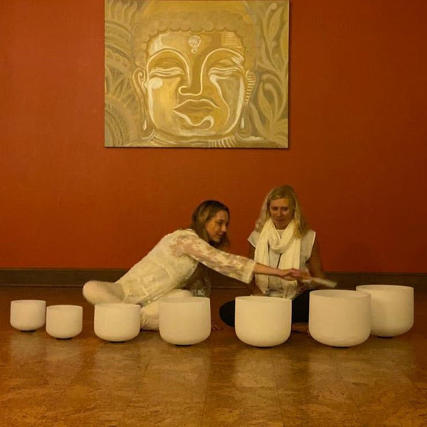 Quartz singing bowl session led by two facilitators in a warm-toned studio space.