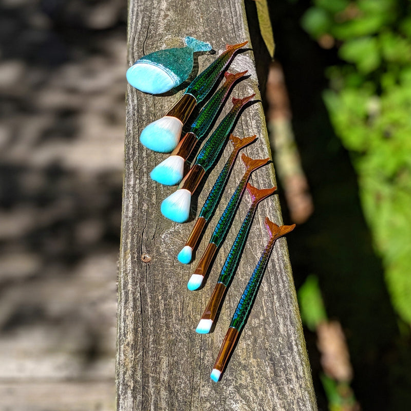 Mermaid brush set arranged in a row with reflective handles and light blue bristles glowing in the sun.