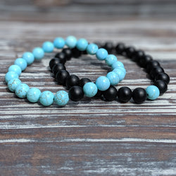 Turquoise and black beaded stretch bracelet set resting on rustic wood, symbolizing balance and duality.