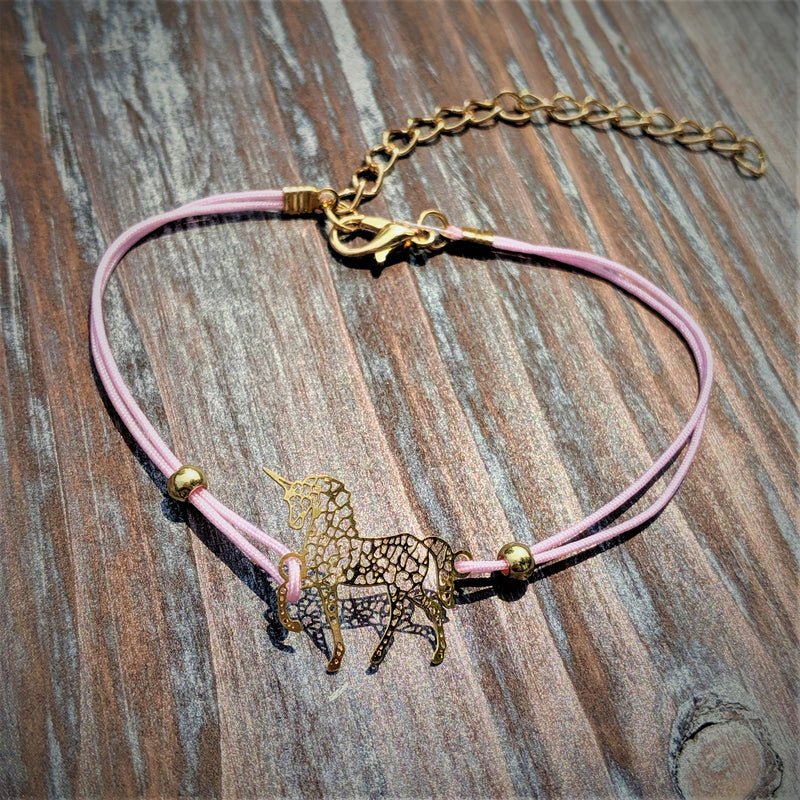 Unicorn Love Bracelet Set laid flat with pink cord, heart, and pineapple charms on wood background.