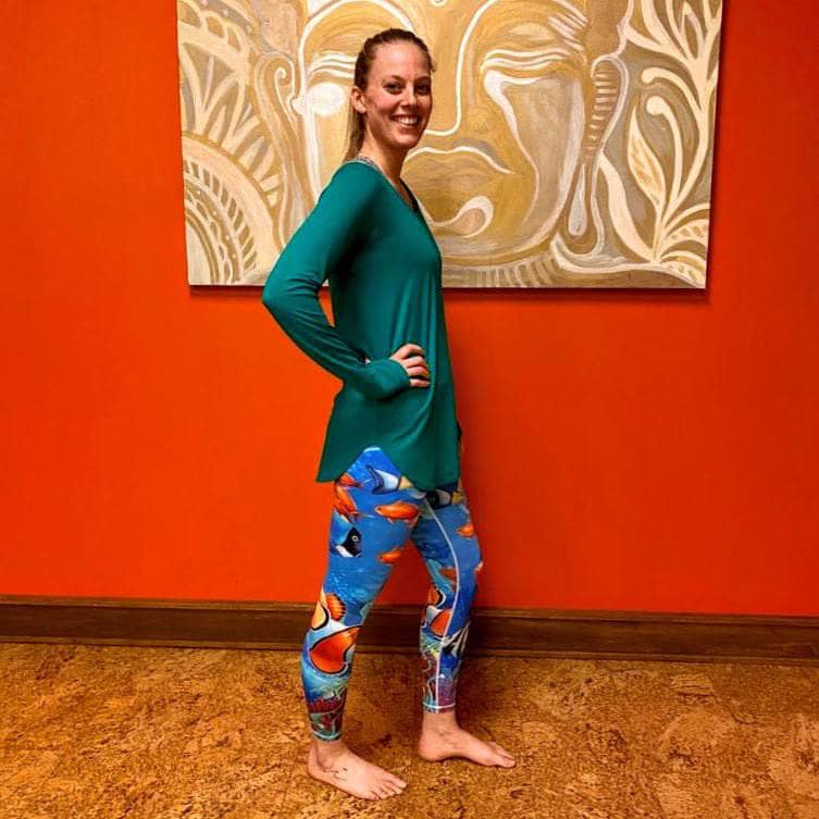 Model in side view smiling in Tropical Sea Leggings, highlighting colorful reef fish and flattering fit.
